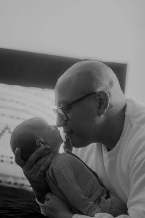 Black and white photo of father sharing a gentle moment with newborn.