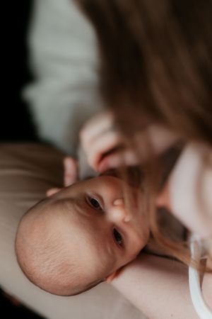 Close up portrait of baby looking at camera while parent leans in.