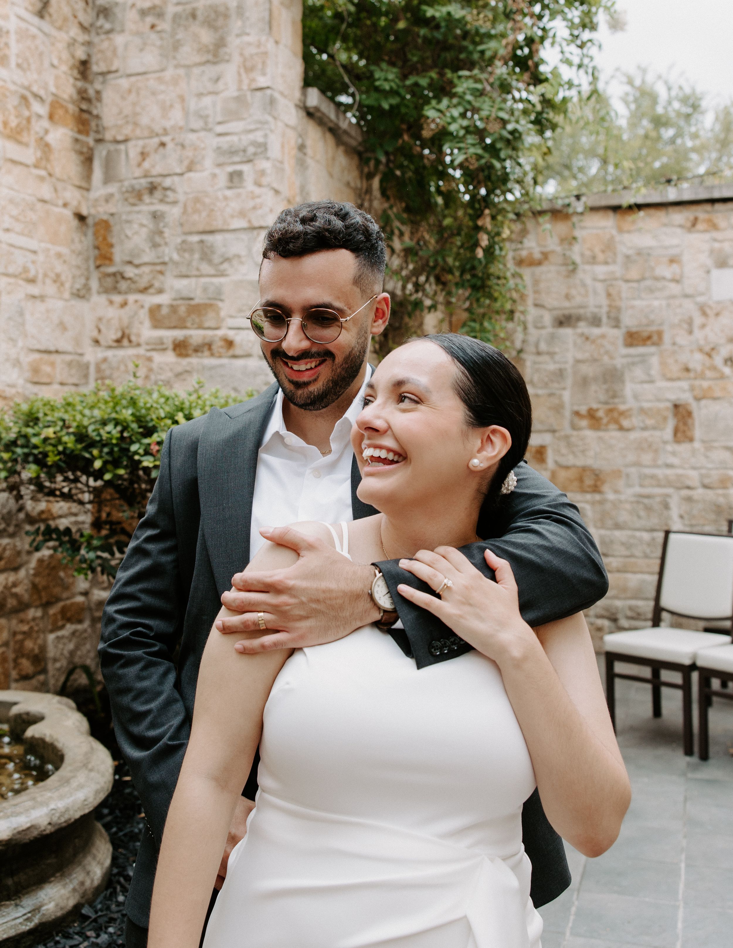 San Antonio Wedding Photography. A couple sharing a candid moment of laughter in front of a stone wall.