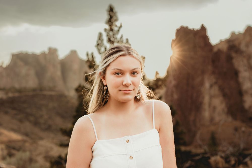 A bride in a white dress poses in a desert landscape during golden hour sunset.