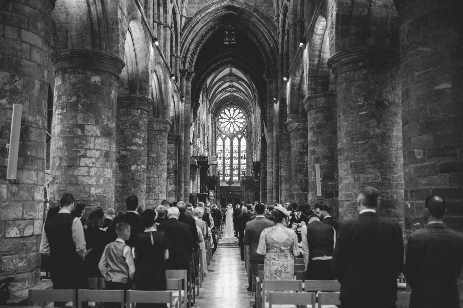 A couple stands in front of the grand St Magnus Cathedral with its red sandstone architecture in Orkney, Scotland.