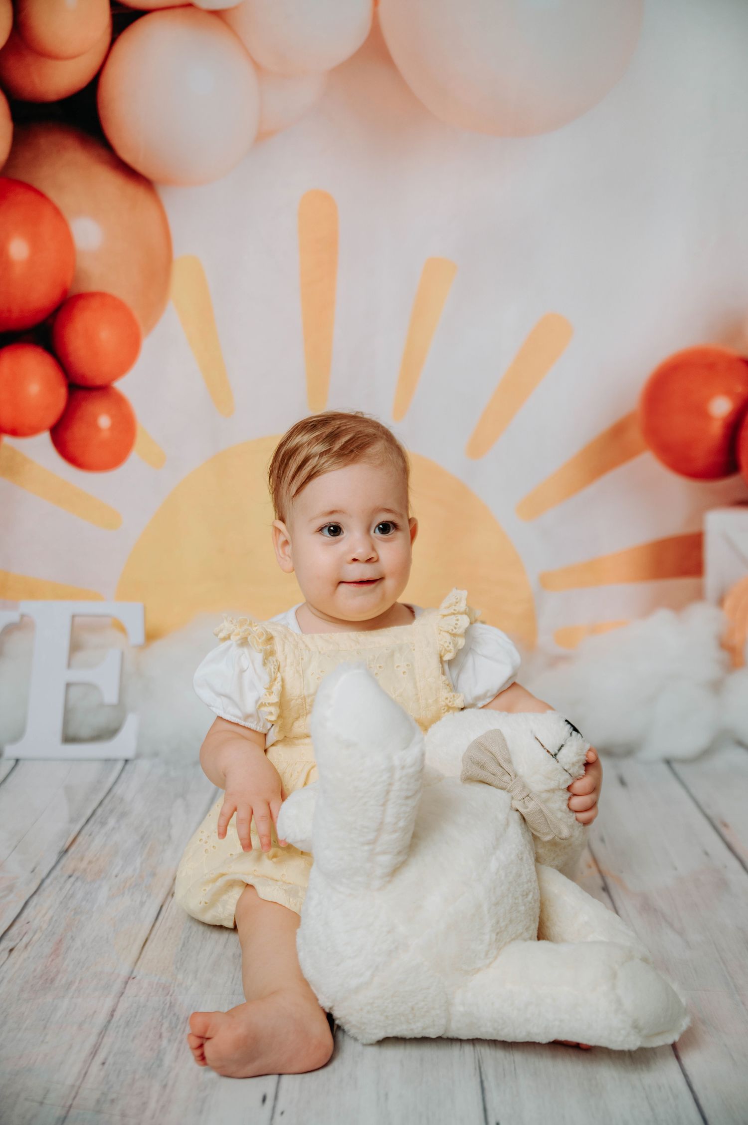 Sunset-themed photo setup with orange balloons and plush white bunny toy.