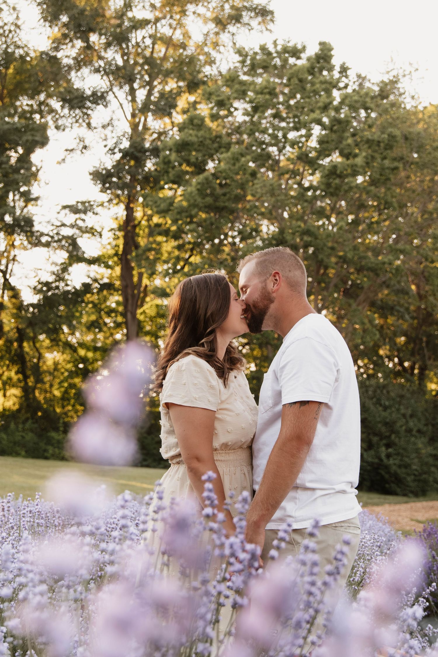 Romantic portrait among blooming lavender flowers at sunset in a garden setting.