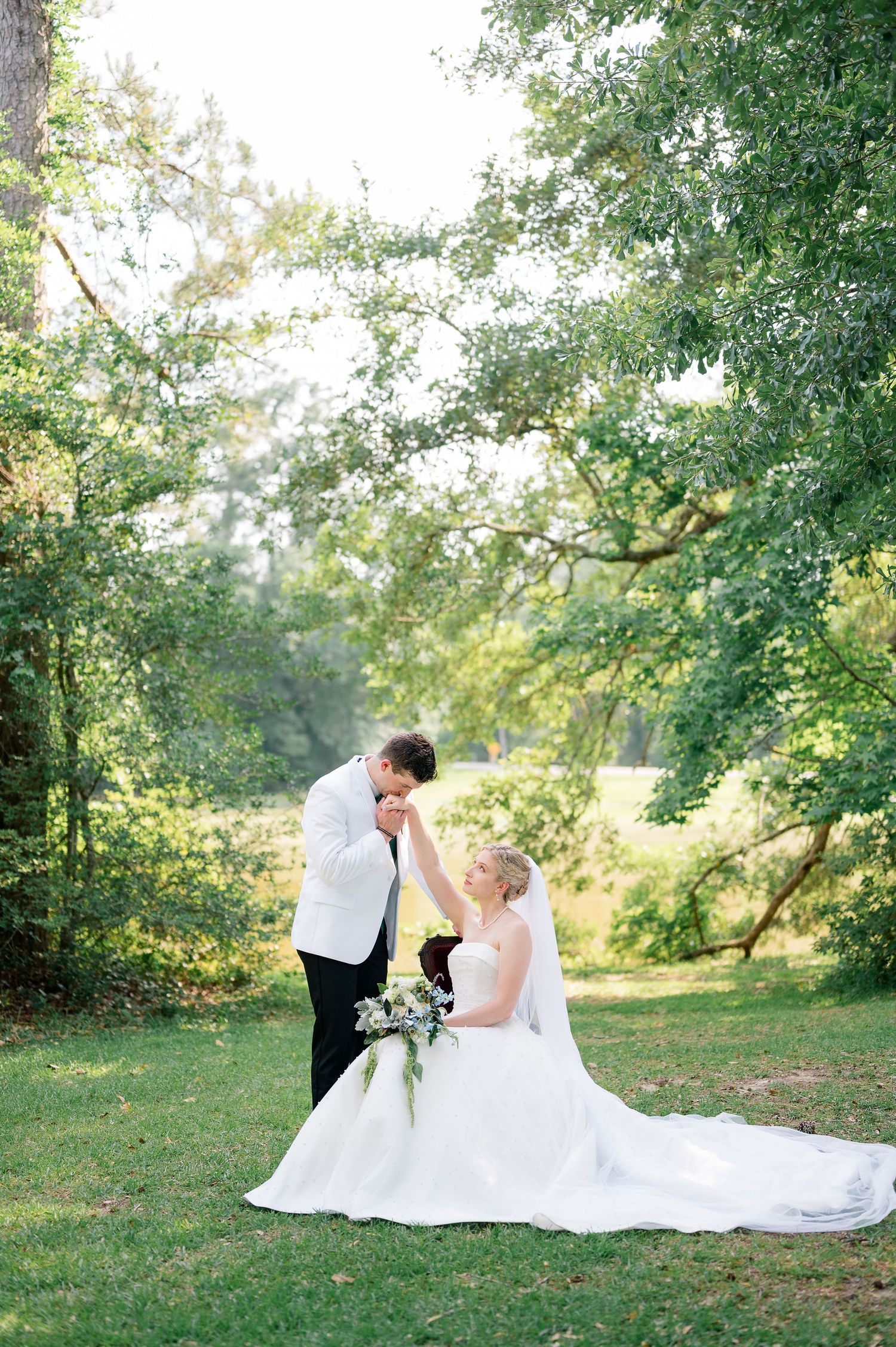 Romantic wedding portrait in golden field with bride holding bouquet and groom in western attire.