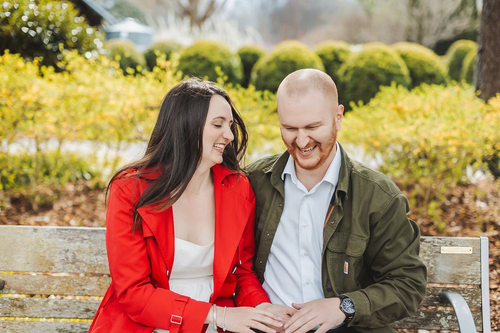 Couple sharing intimate moment while sitting on bench in sunny garden setting.