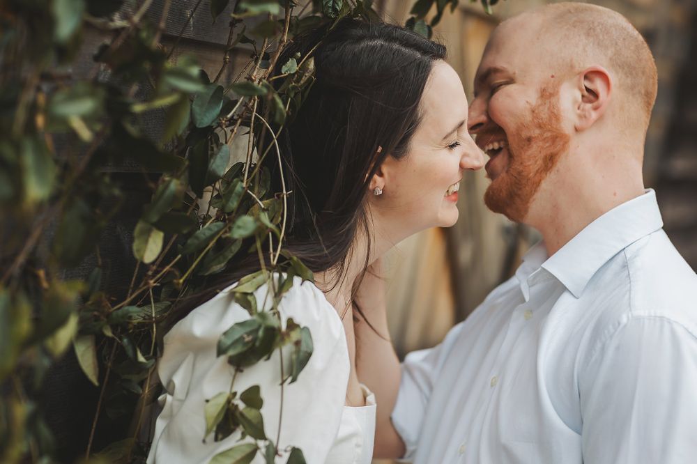 Intimate moment between couple with greenery and rustic barn setting.