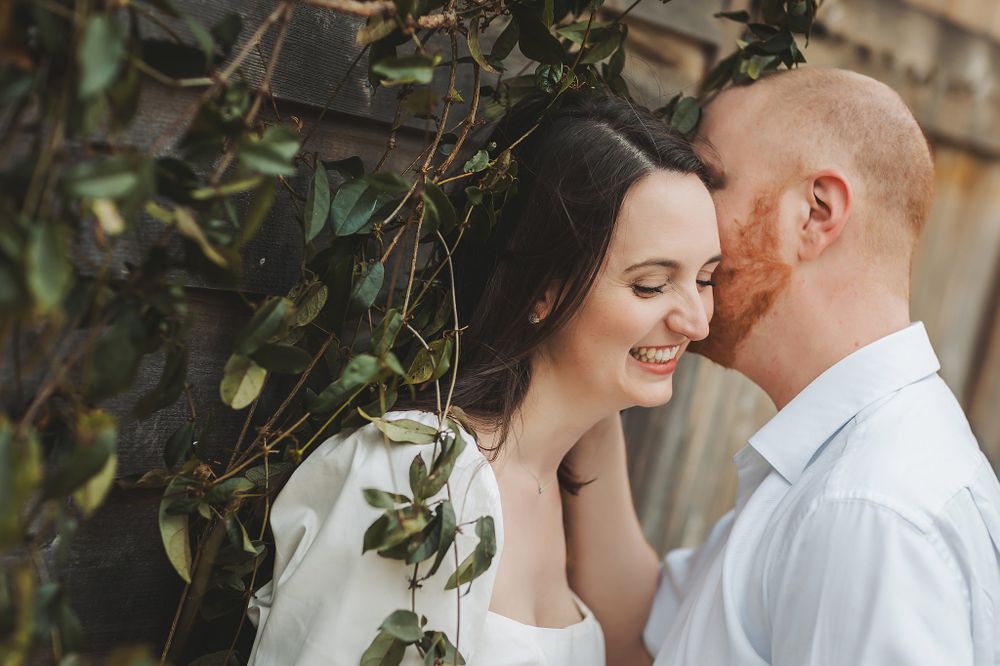 Romantic couple sharing intimate moment surrounded by green foliage.