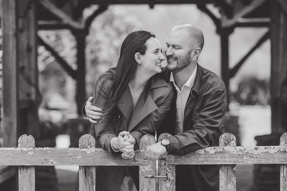 Couple shares intimate moment along rustic wooden fence during photo session.