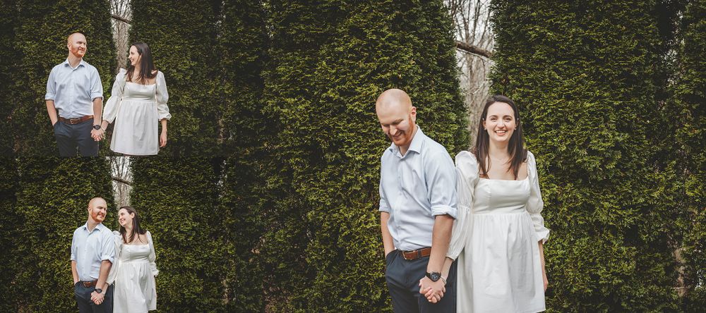 Couple posing together in front of lush green evergreen trees and shrubs.
