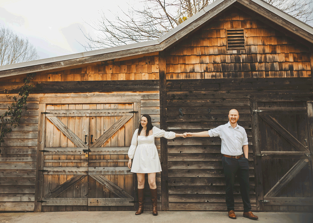 Rustic wooden barn with weathered siding provides backdrop for outdoor portraits.