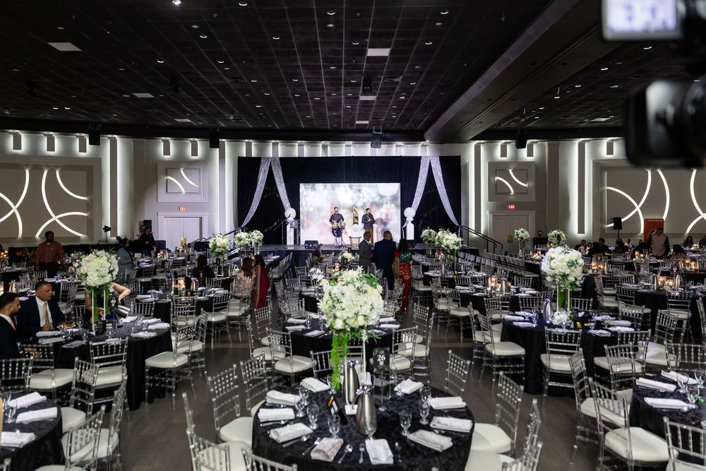 A modern banquet hall with dark tables and chairs arranged in rows for a large event or conference.