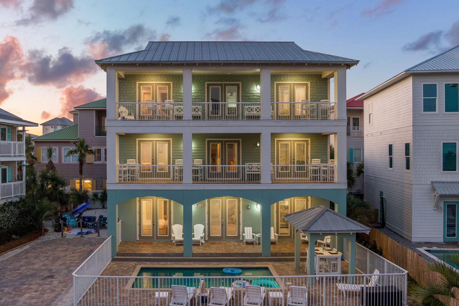 Three-story luxury beach house with private pool and multiple balconies at sunset.