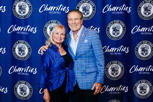 Couple posing together at Charities Recovery event, woman in blue jacket and man in plaid blazer smiling.