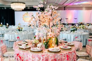 Elegant wedding reception table with pink floral centerpiece and crystal chandelier overhead.