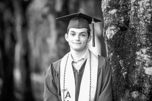 Black and white graduation portrait in natural outdoor setting.