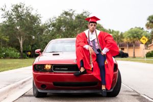 Red Dodge Challenger parked outdoors with graduation-themed photo composition.