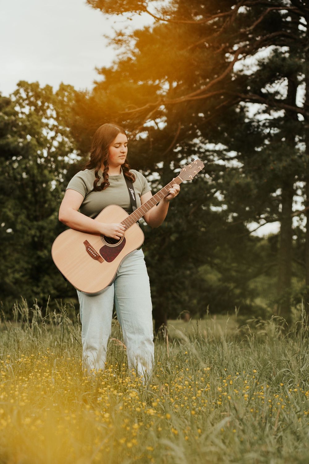 senior portrait with a guitar in a field with yellow flowers