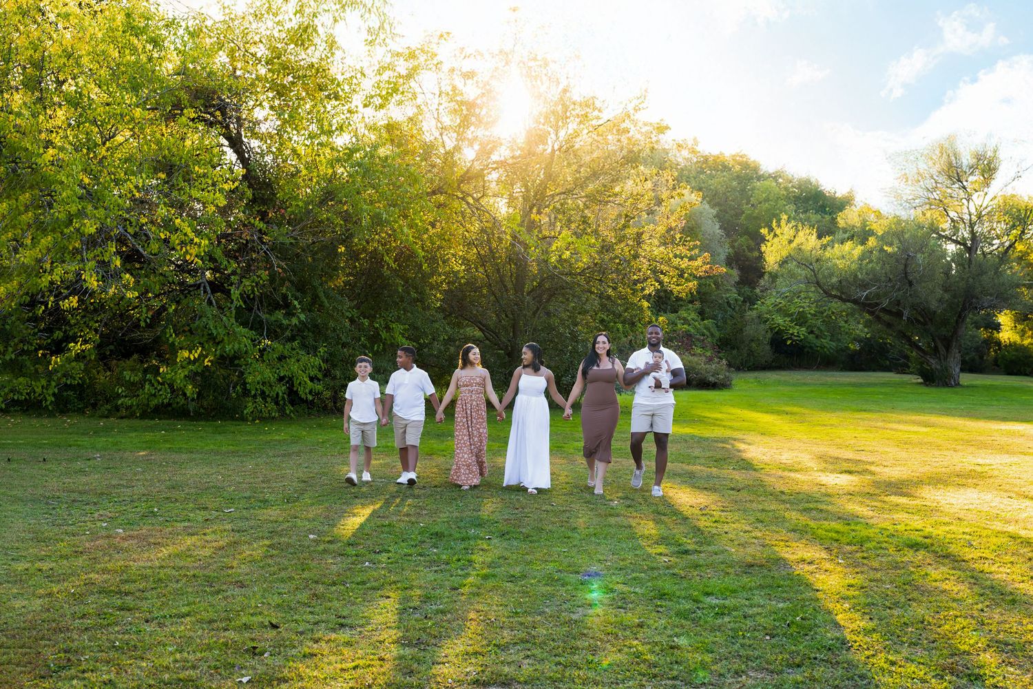 A family in matching purple outfits pose together on a lush green garden path during a sunny summer day.