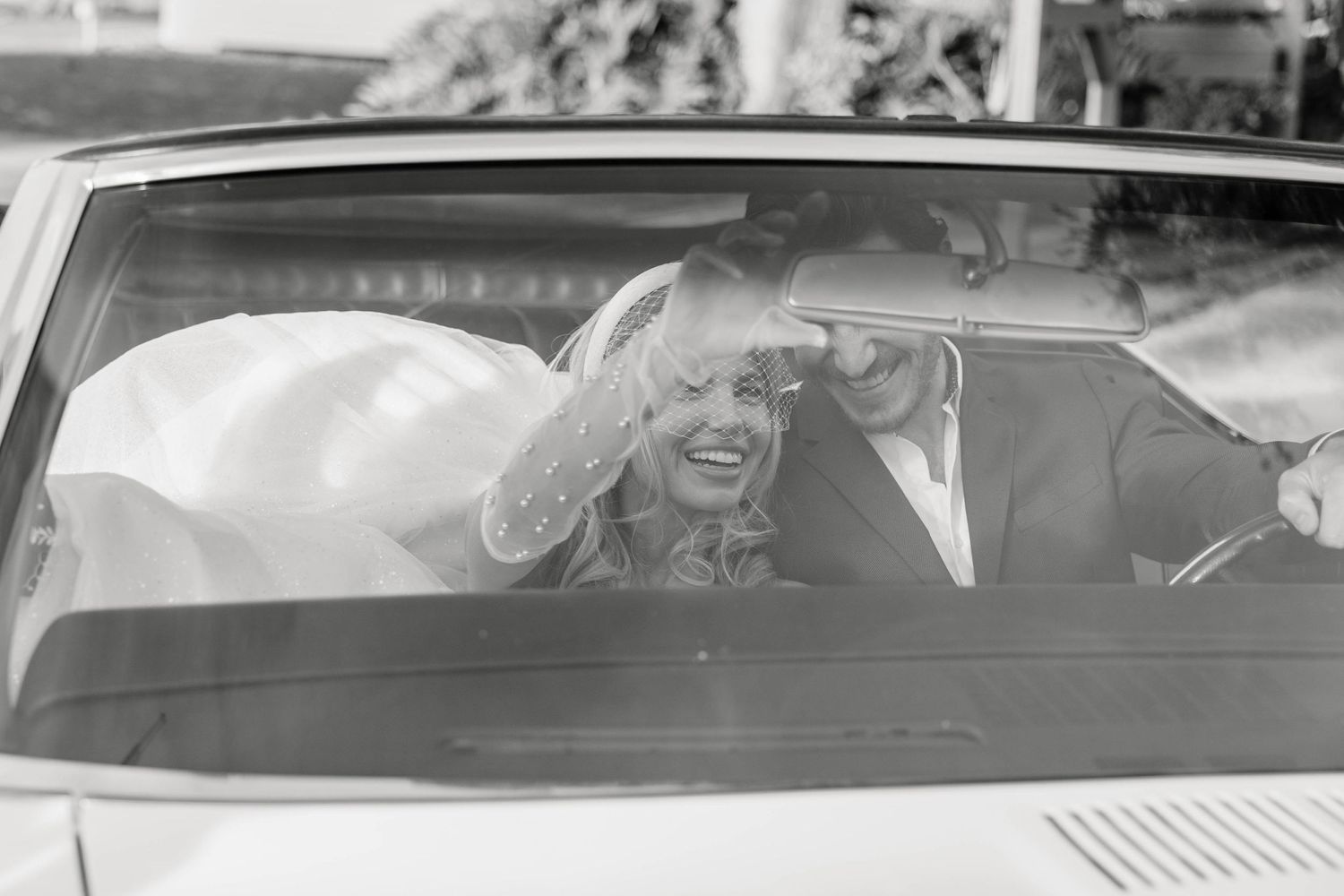 bride and groom sitting in a vintage car together. Captured by St Petersburg wedding photographers in Florida