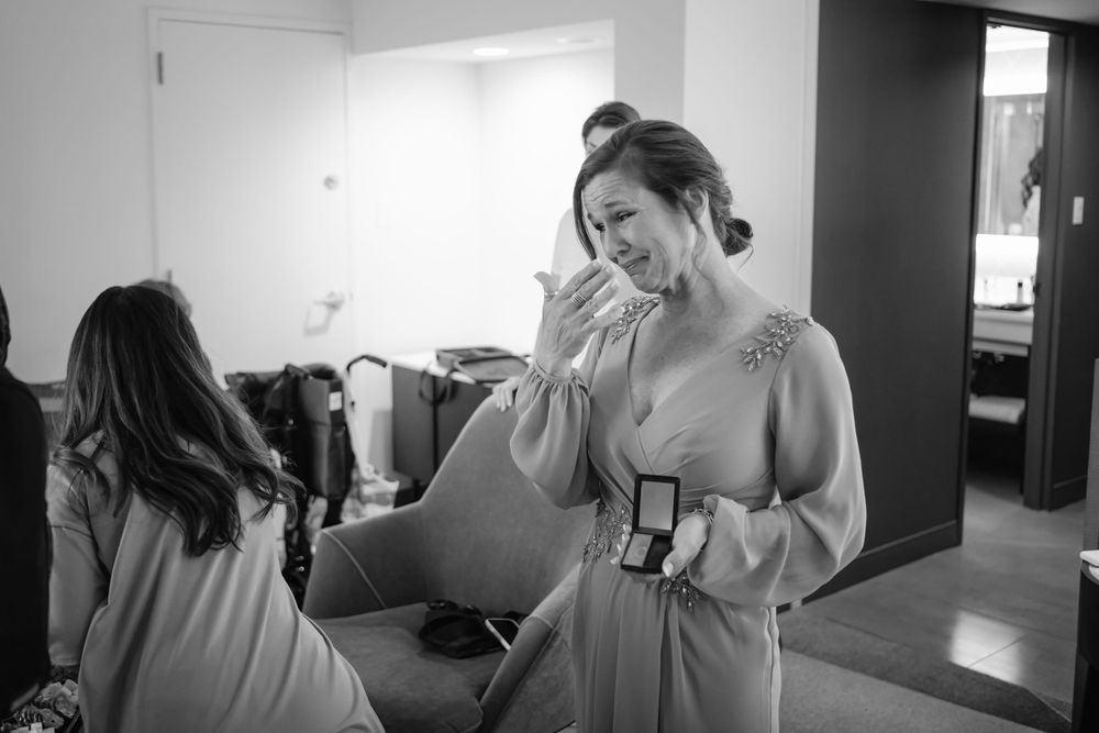 A candid black and white photo shows a woman in a light-colored dress crying during what appears to be a backstage moment.
