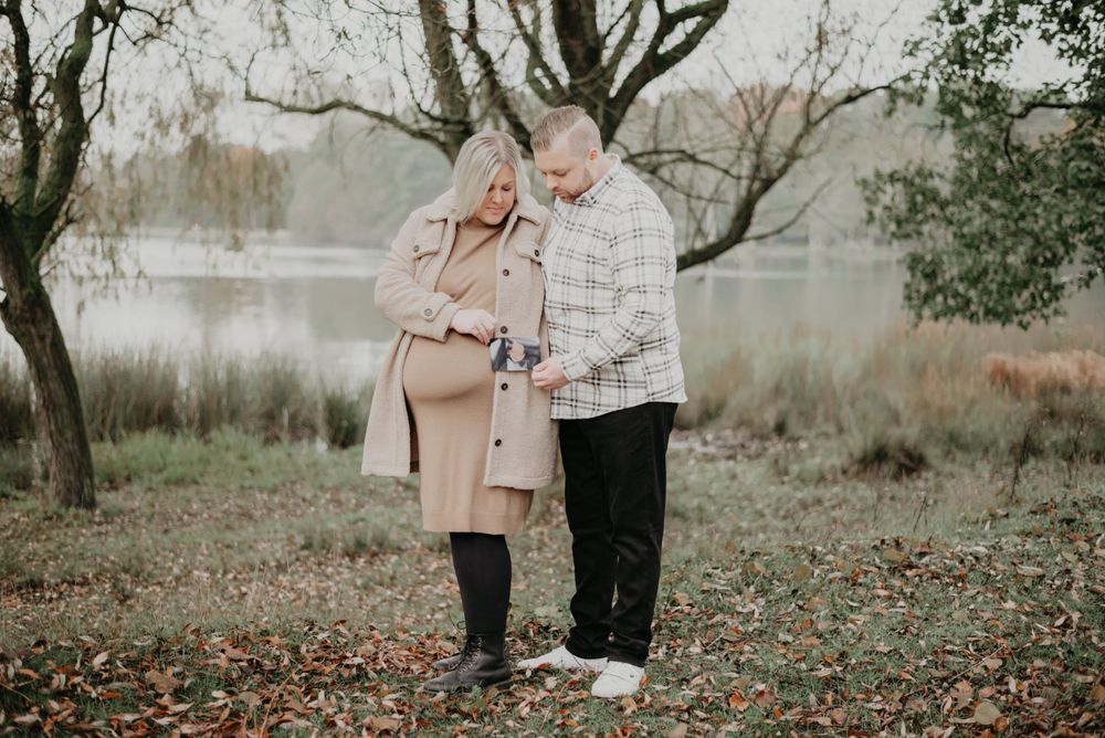 A couple in coordinated outfits sharing a romantic moment by a misty lake.