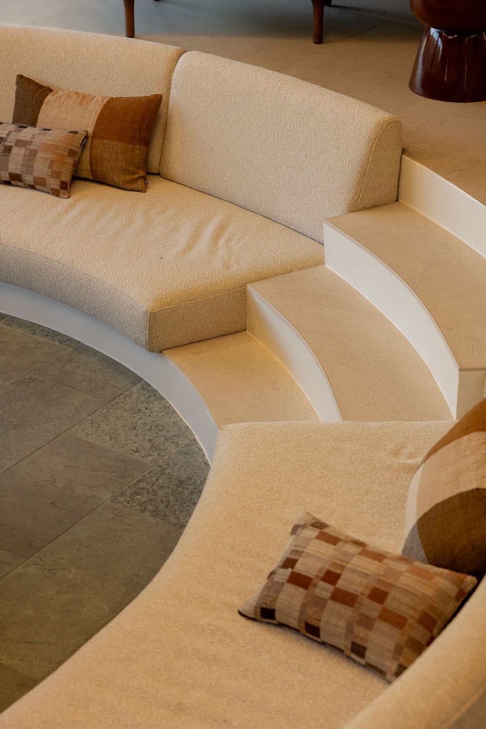 Curved cream-colored sectional sofa with geometric patterned throw pillows and stepped architectural design details.