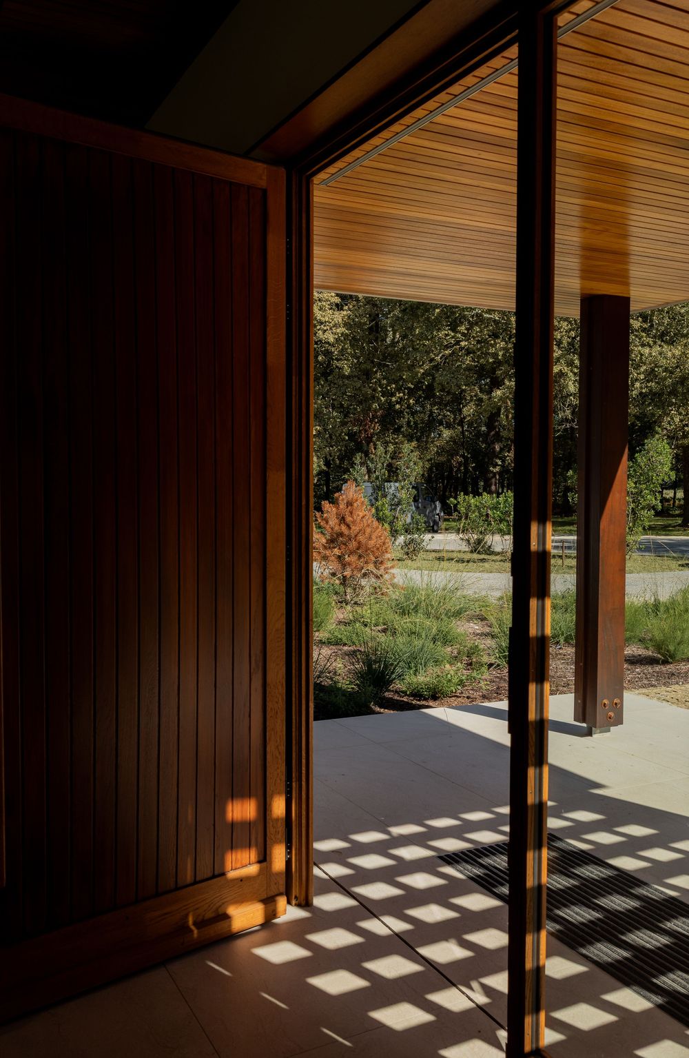 Architectural series showing sunlight casting dramatic geometric shadows through wooden beams onto a concrete floor.