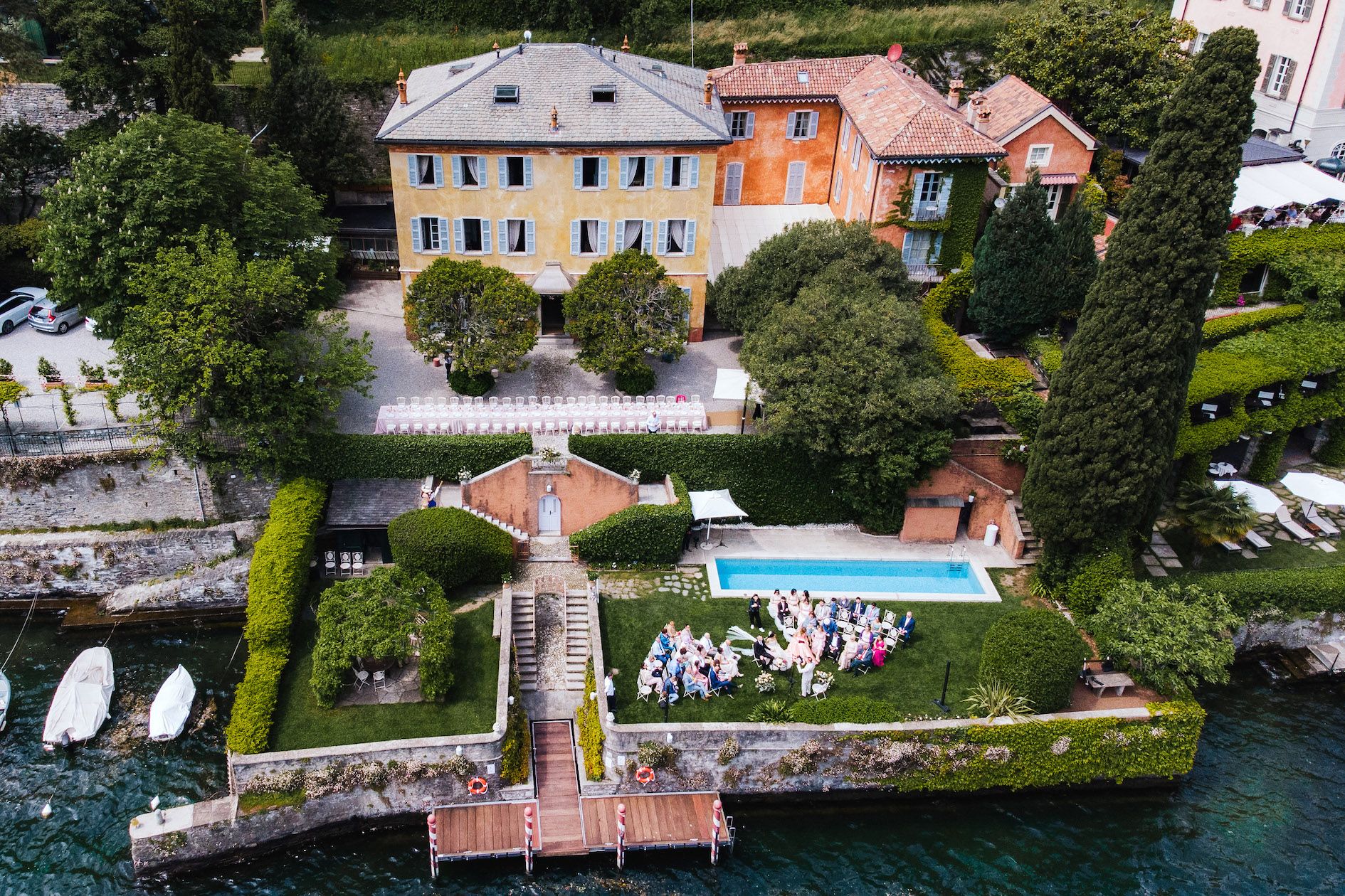 Villa Regina Teodolinda view of luxury waterfront villas with private docks along Lake Como's shoreline in Italy.