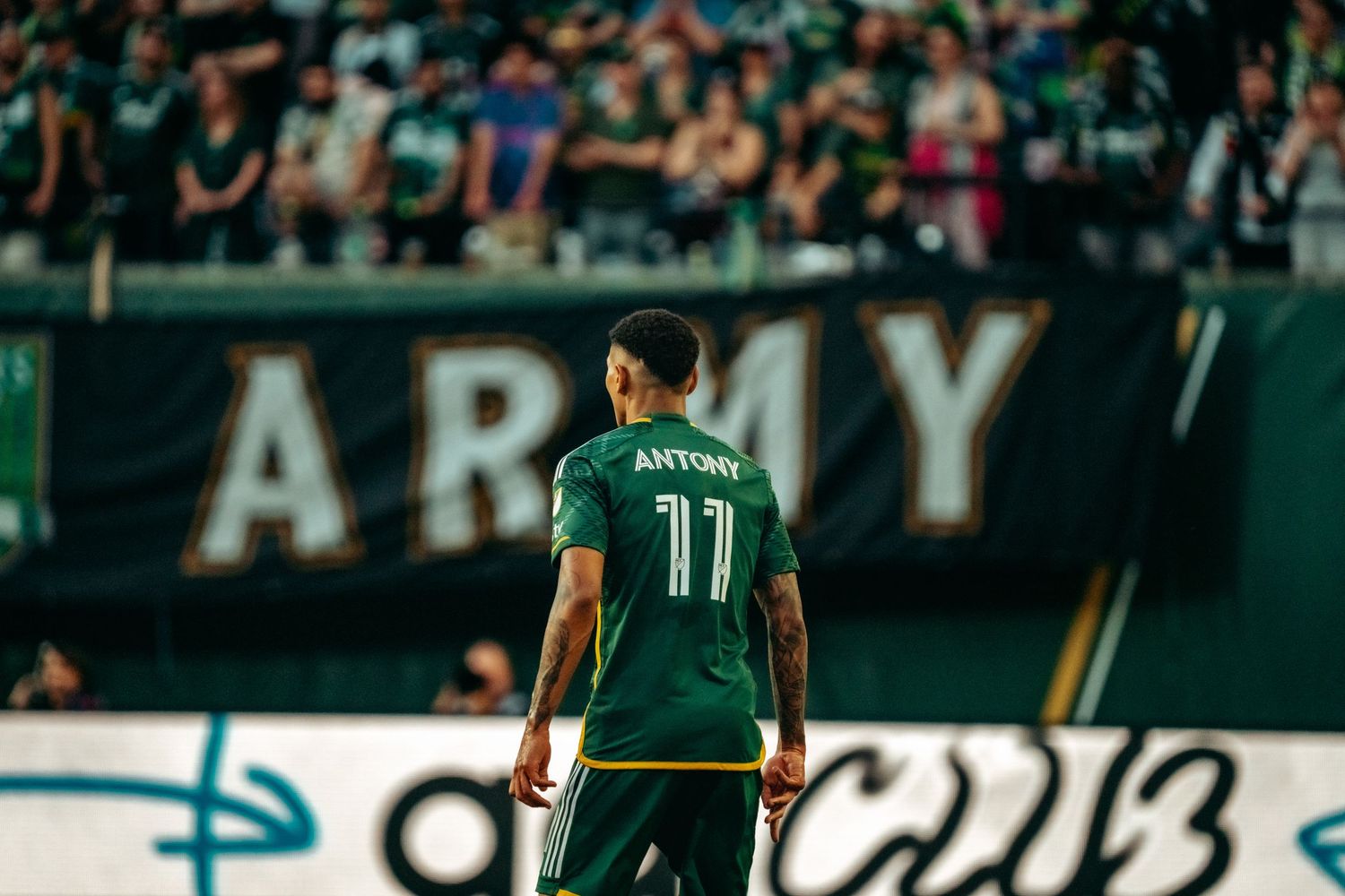Portland Timbers player Antonio wearing number 11 green jersey stands on field before MLS crowd.