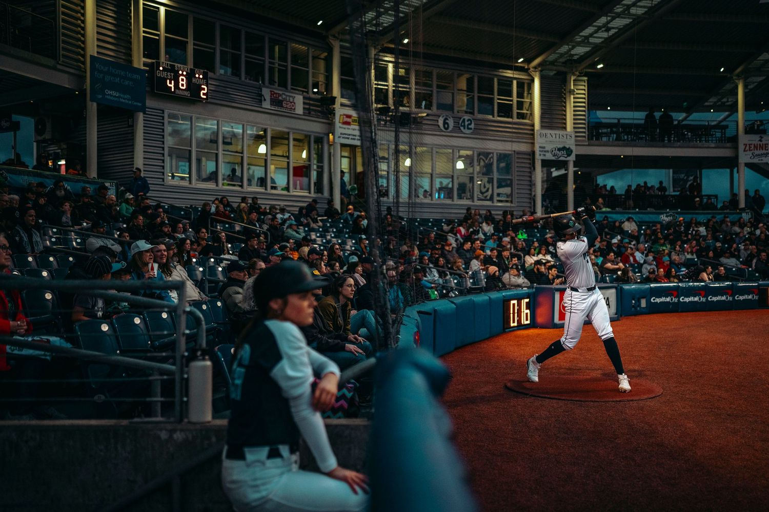 Baseball batter stands at plate in packed stadium under bright lights during a professional night game.
