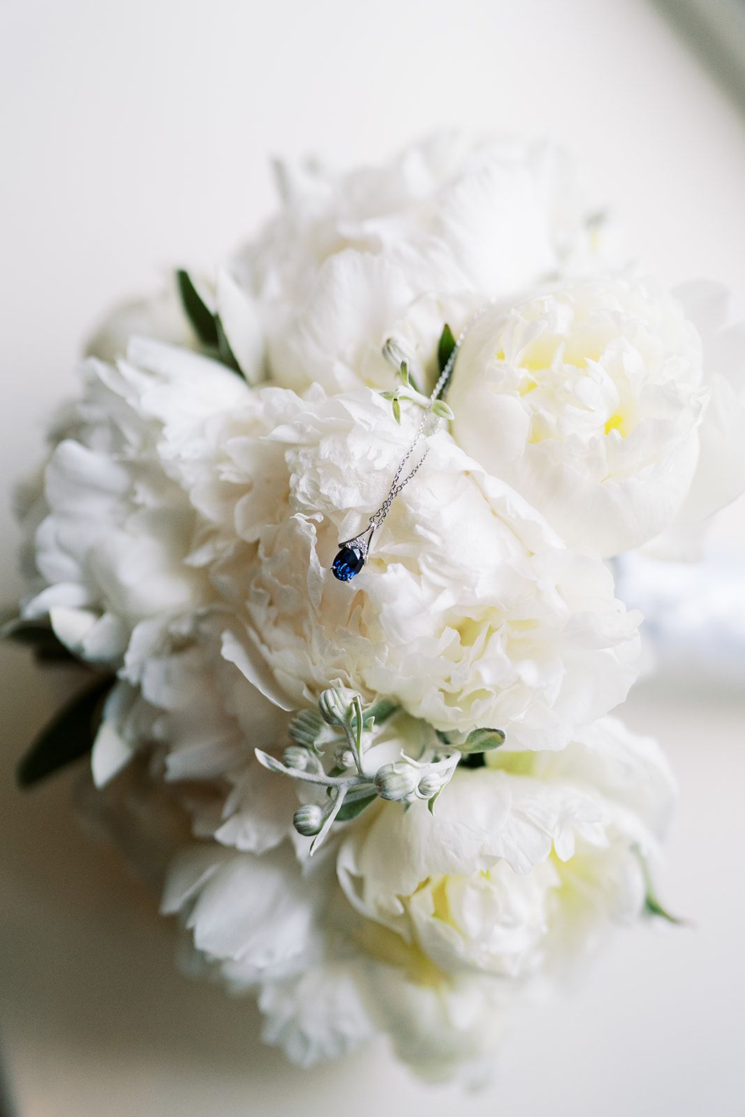 A delicate white peony bouquet with a small blue accent jewel.