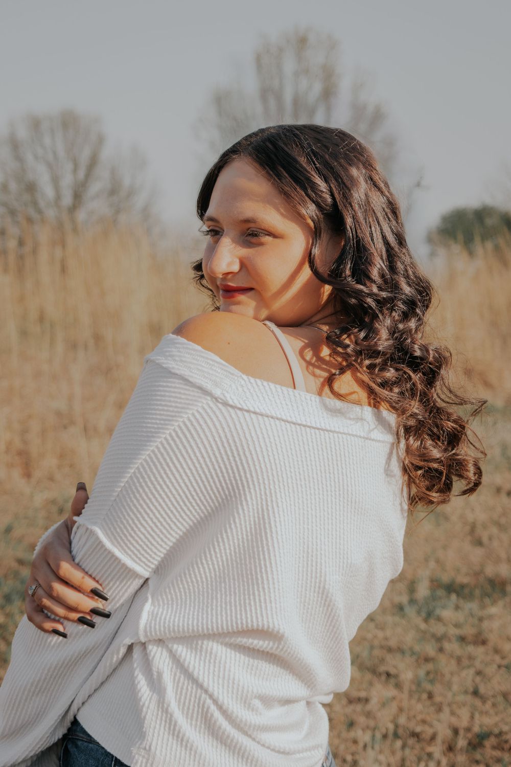 Portrait in autumn setting with warm sunlight and dry grass background.