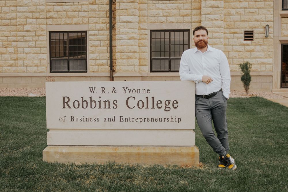 Stone sign for Robbins College of Business and Entrepreneurship with building in background.
