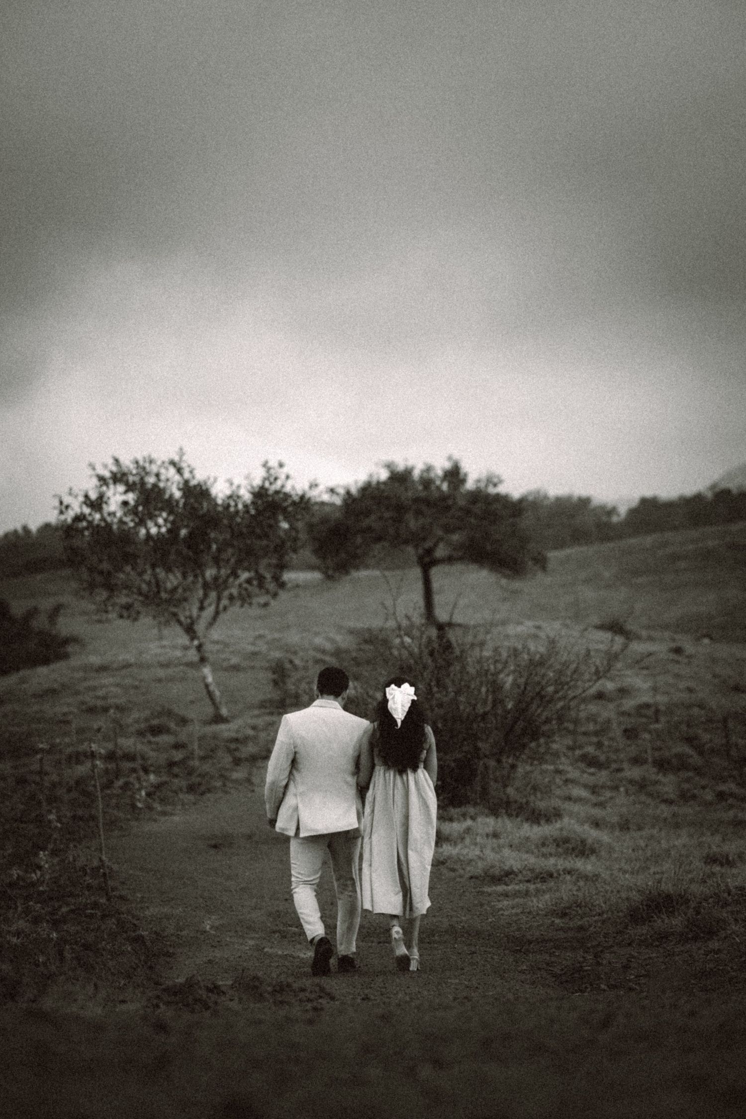 Black and white landscape photograph of couple walking through misty hillside.