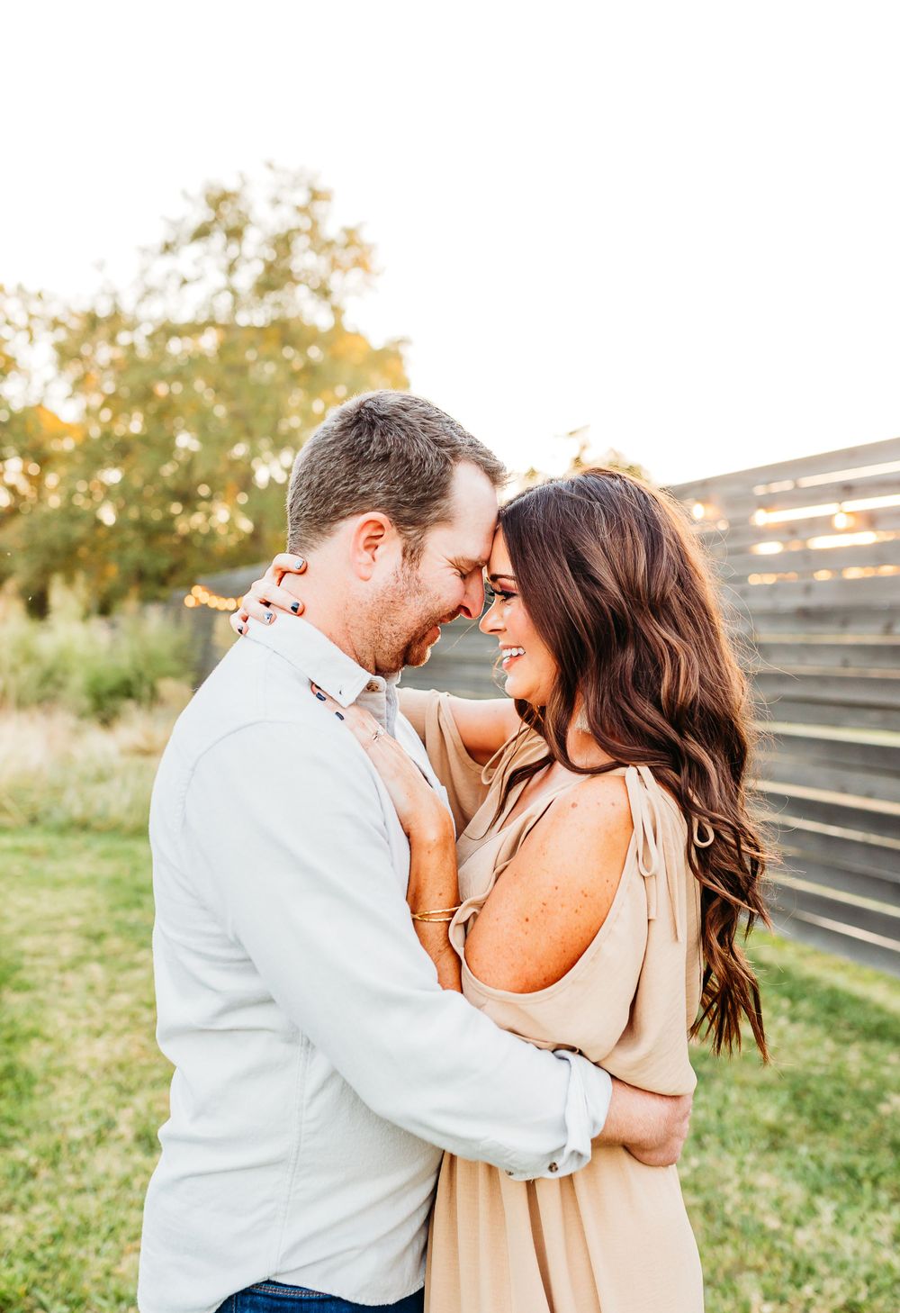A romantic couple shares tender moments in a series of photos taken outdoors against a rustic wooden fence at sunset.