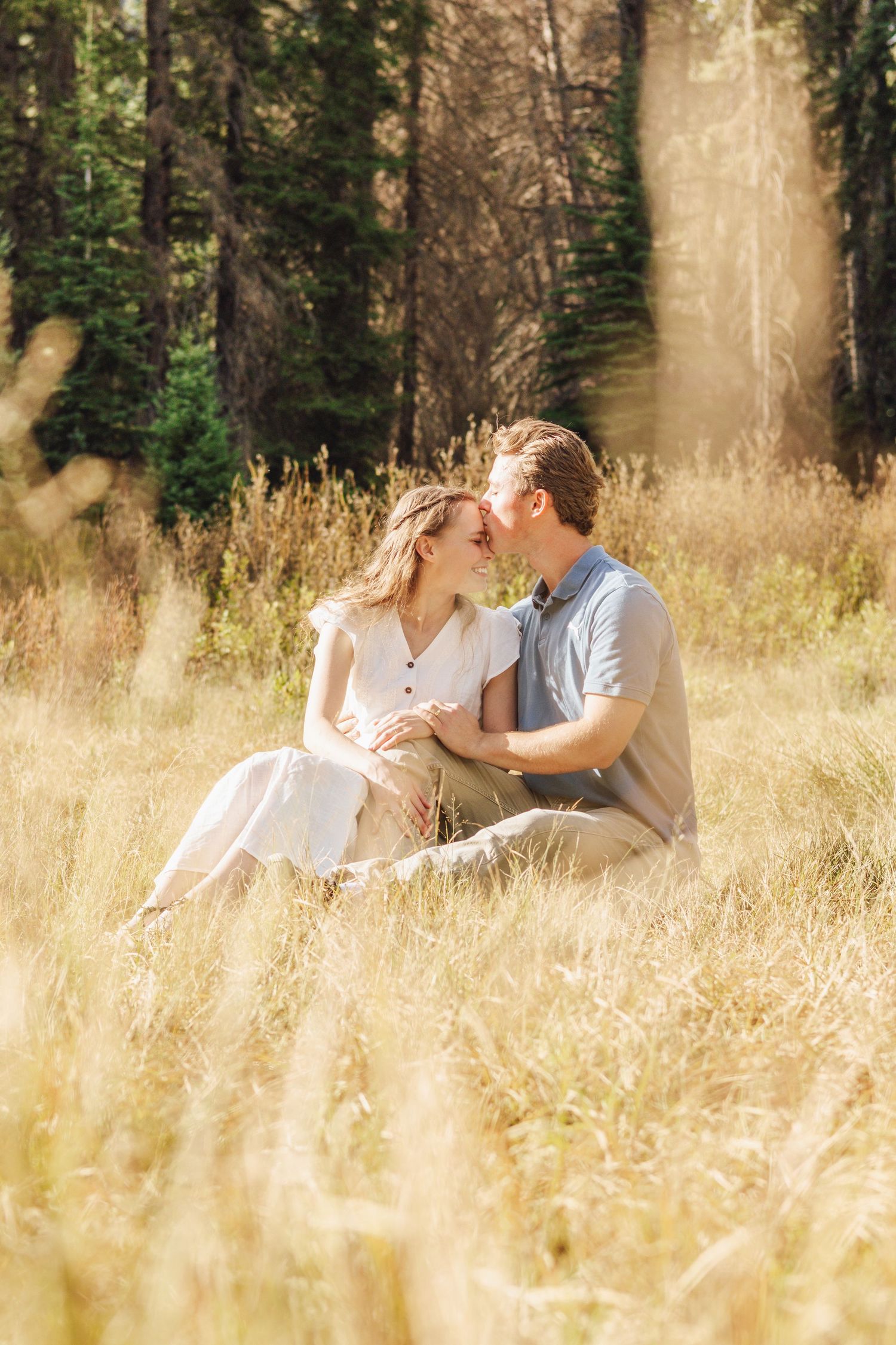 Groom dipping bride for a kiss in front of a stone building with colorful tulip garden.