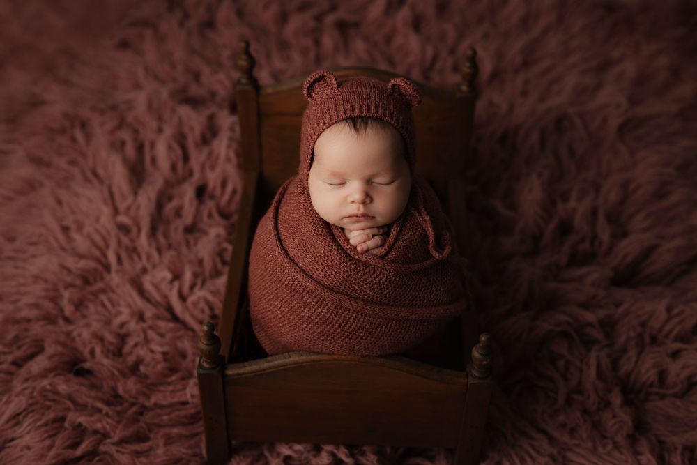 A series of seven professional newborn photography portraits in warm brown tones against a textured backdrop.