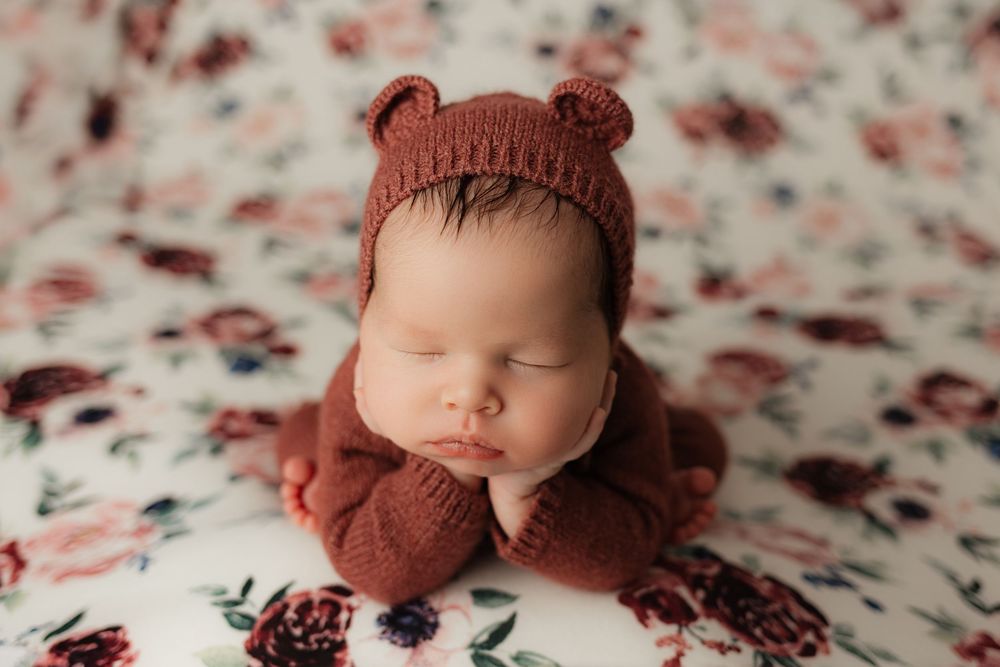 Newborn baby photography session with rustic props and textured blankets in warm earth tones.