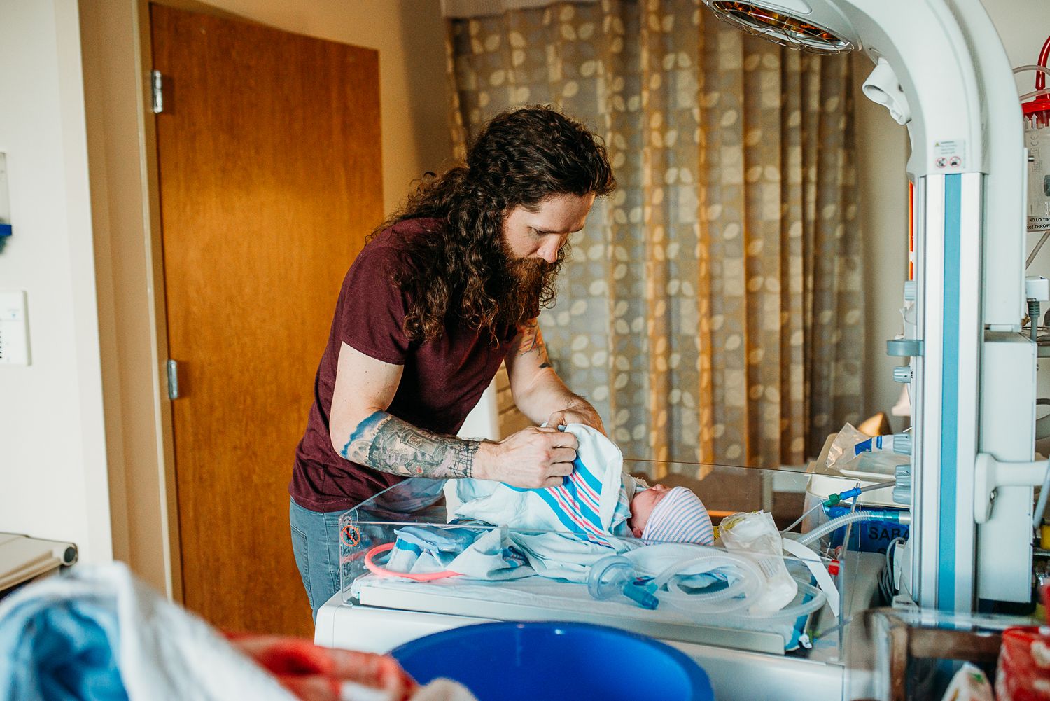Person folding laundry in hospital room with natural lighting.