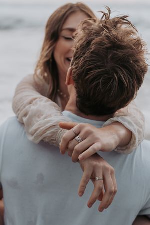 Close-up of hands and embrace against a light colored background.