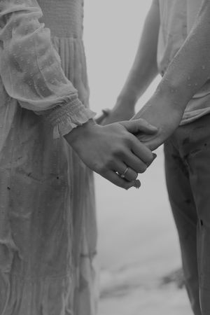 Close-up of hands holding together against a misty gray background.