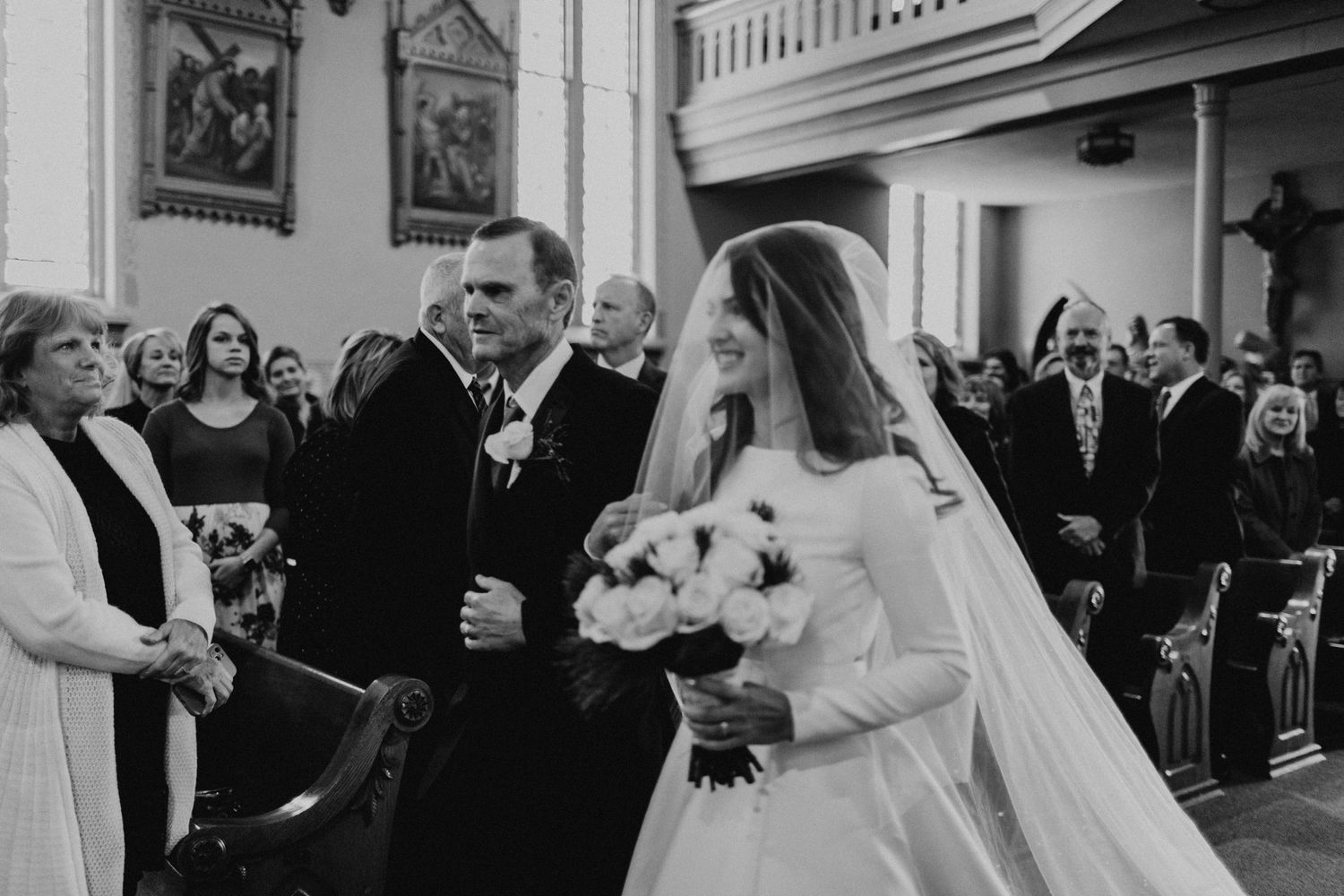 A bride and groom walking down the church aisle surrounded by wedding guests.