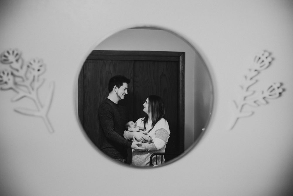 A black and white family portrait captured through a circular frame with floral accents on the wall.