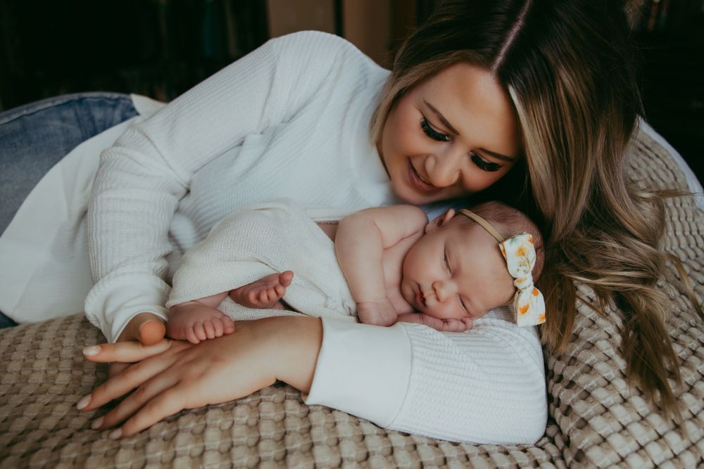 Mother and sleeping baby share an intimate bonding moment on a cozy knit blanket.