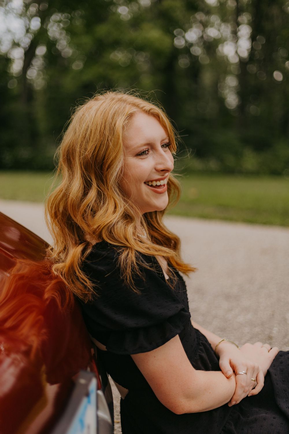 Woman in black dress with flowing hair outdoors on sunny day.