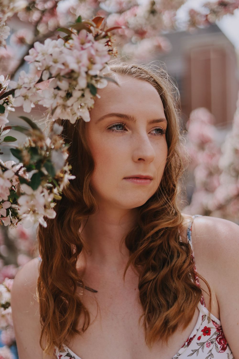 Person poses near blooming cherry blossoms in springtime.