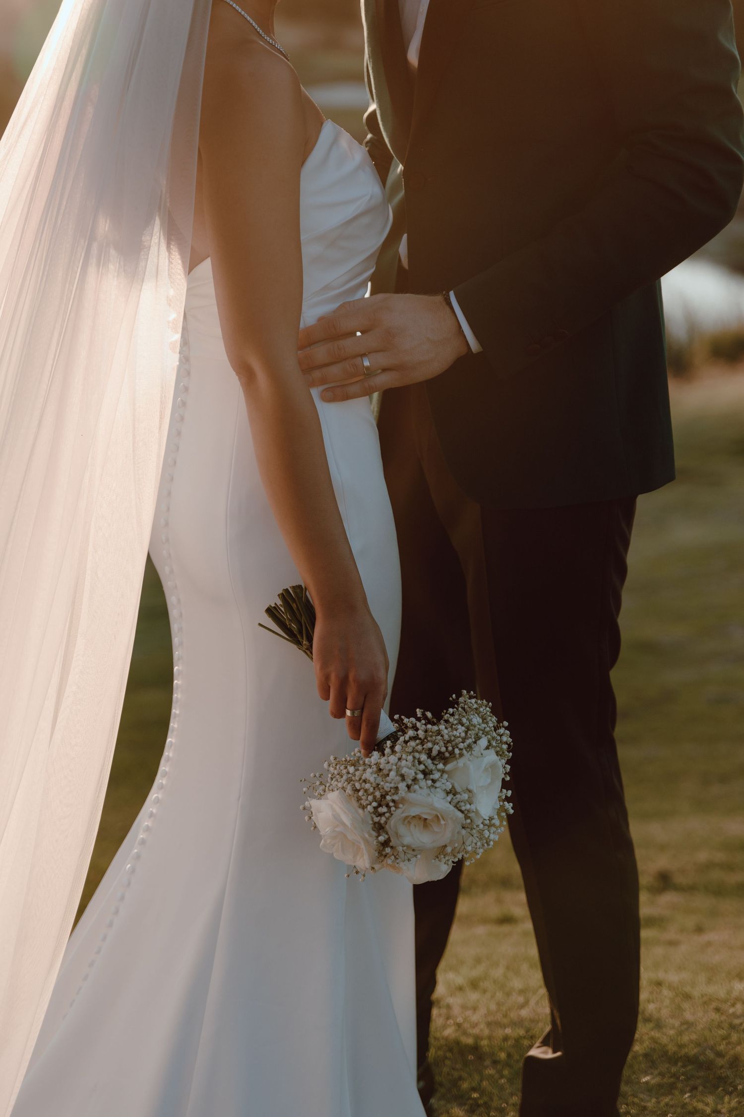 A close-up shot of a bride and groom embracing, with the bride holding a white floral bouquet.