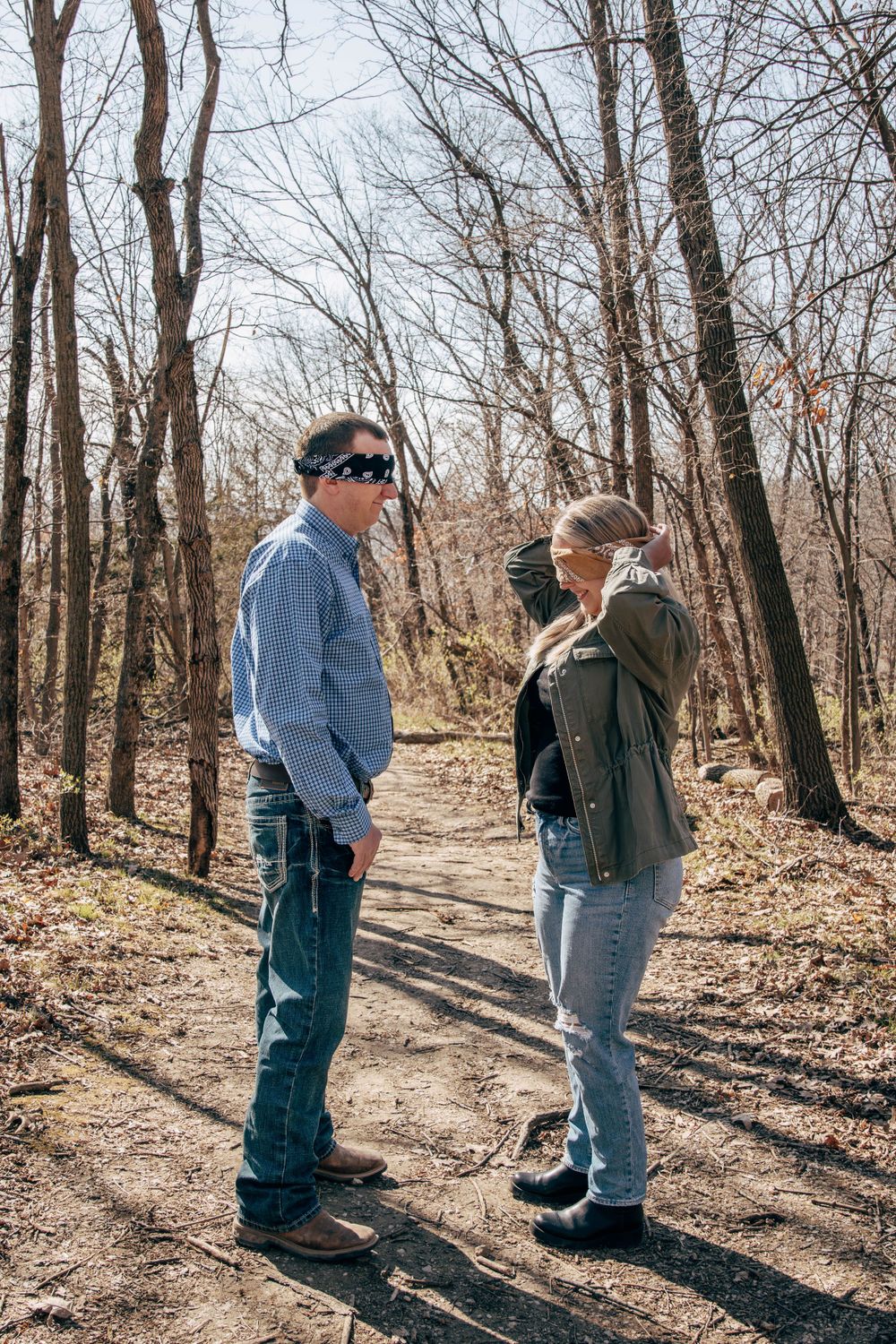 Two people having a conversation while standing on a forest path with bare trees.