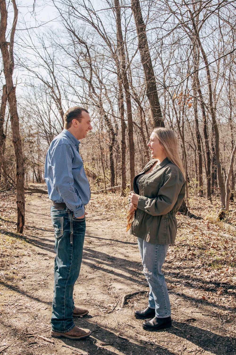 Two people engaged in discussion while standing on a hiking path in the woods.