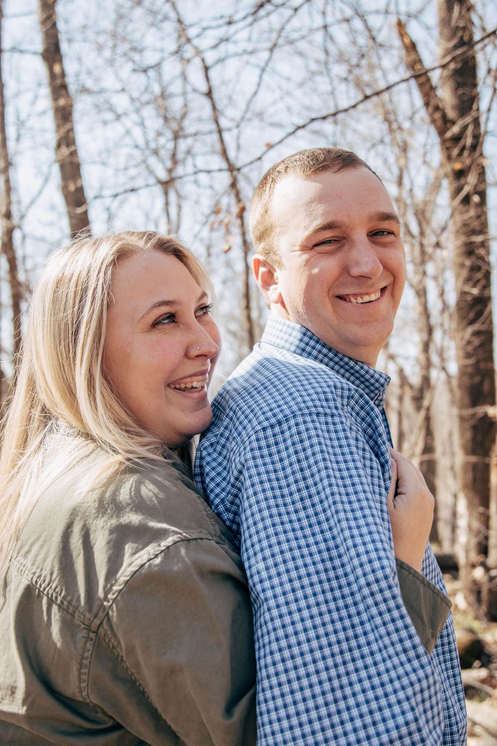 A joyful couple embracing and laughing together on a sunny woodland path.